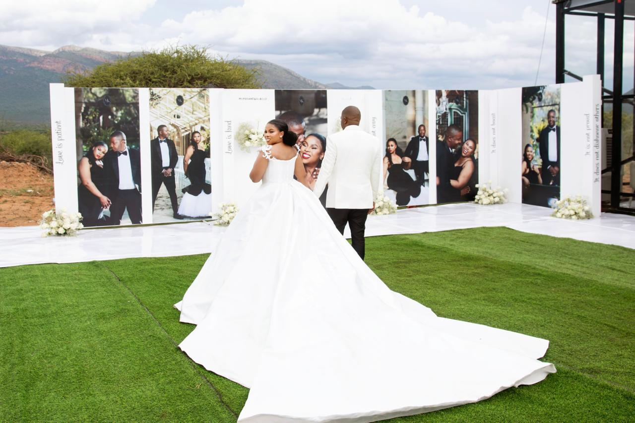 Bride and groom in front of a large outdoor portrait wall installation